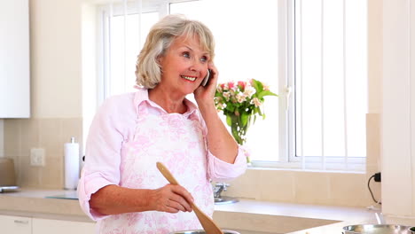 Mujer-Mayor-Preparando-Una-Comida-Y-Contestando-El-Teléfono