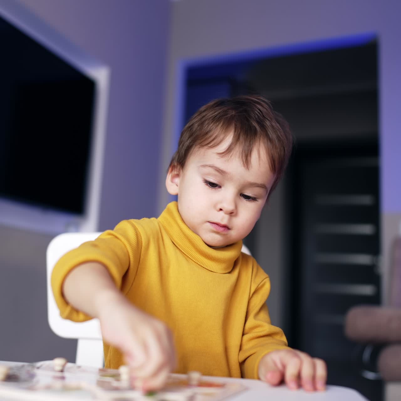 Adorabile bambino con un maglione giallo è concentrato su un gioco a incastro. Bambino che gioca e impara a casa