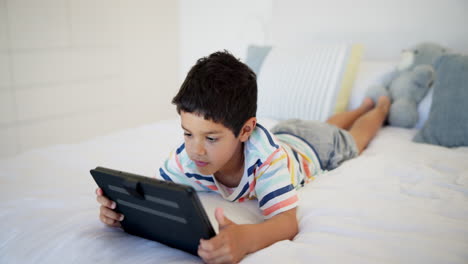 niño usando una tableta en una cama