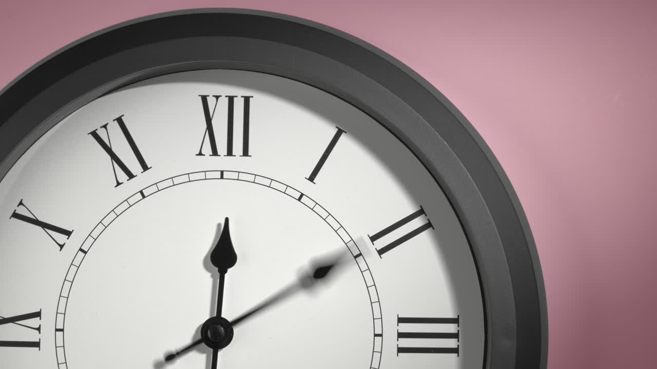 Latinalainen kellotaulu ruusunpunaisella seinällä time lapse -kuvauksena.