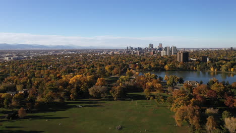 aerial drone shot flying over beautiful denver park in the fall with city skyline in the background