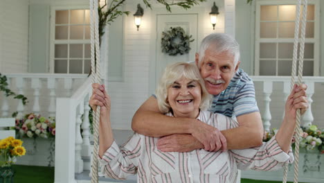 senior couple together in front yard at home. man swinging woman during coronavirus quarantine