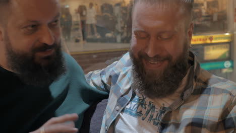 close up view of two white mature bearded men using smartphone together