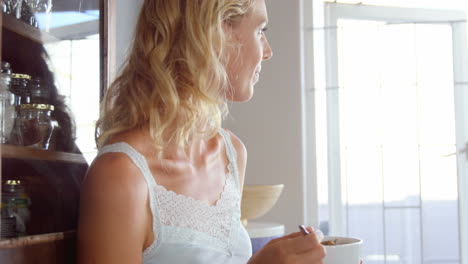 una rubia linda con cereales en la cocina.