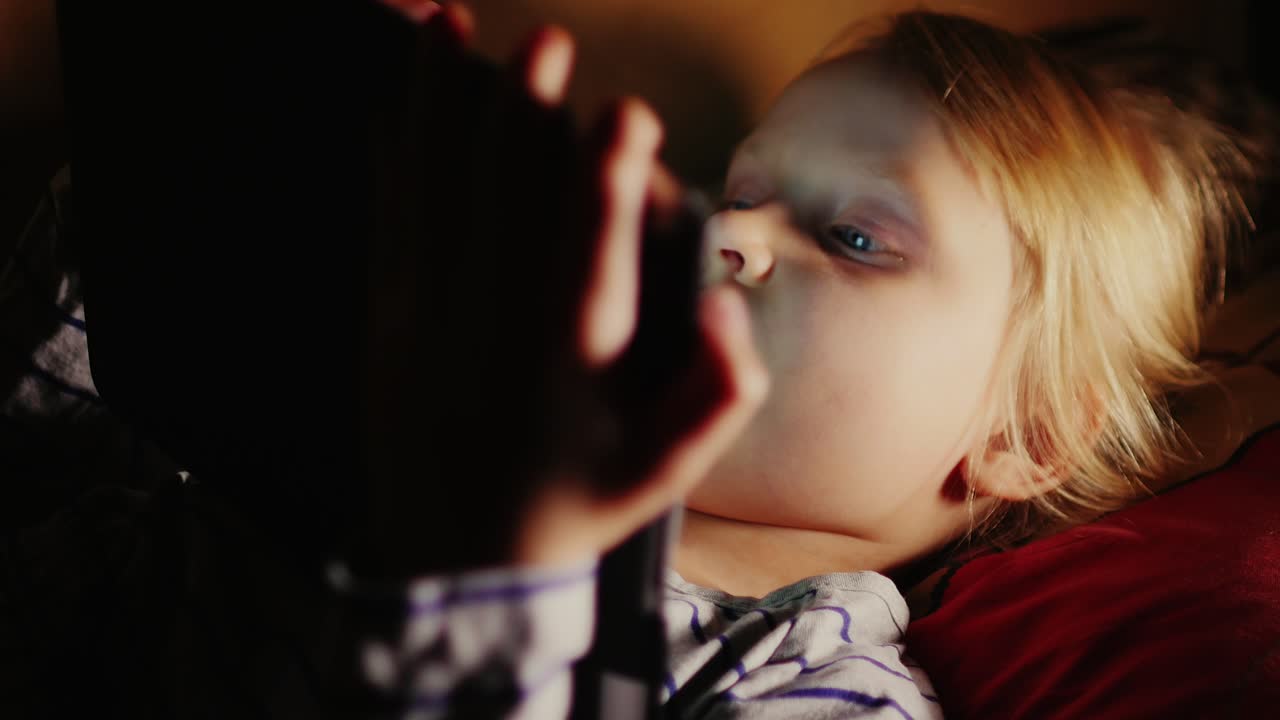 태블릿을 사용하여 침대에 누워있는 소녀