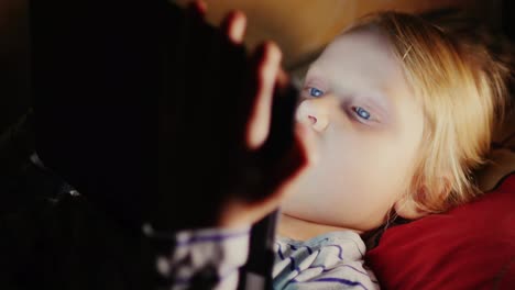 niña acostada en la cama usando una tableta