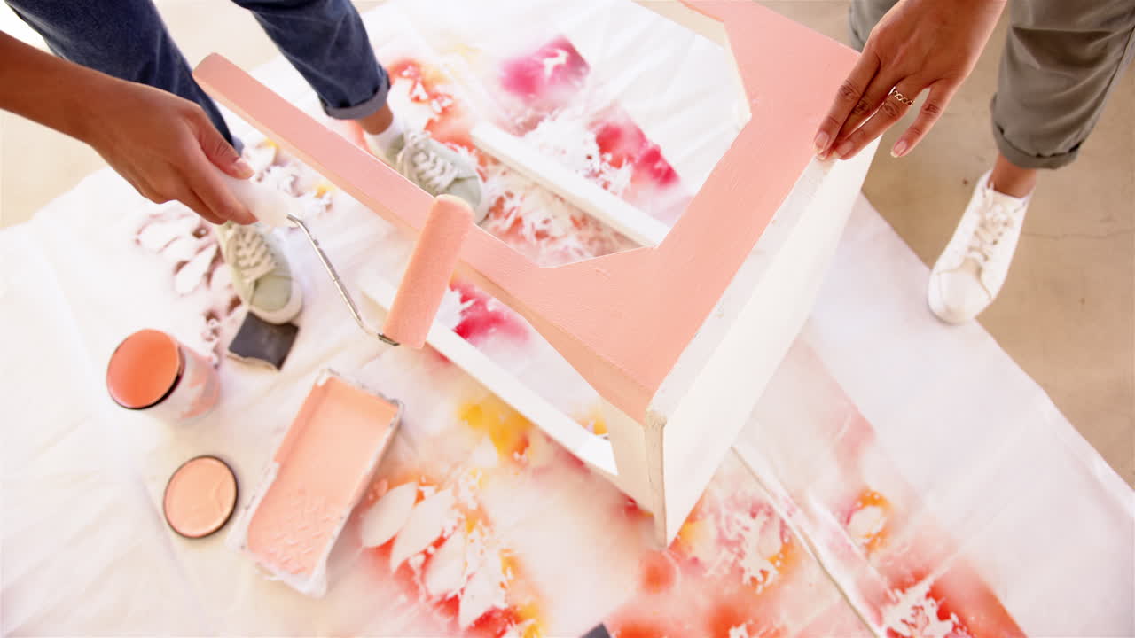 Painting furniture, people using roller brush and pink paint for DIY project
