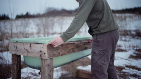 the man is utilizing a collapsible yardstick to measure the dimensions of the homemade hot tub - static shot