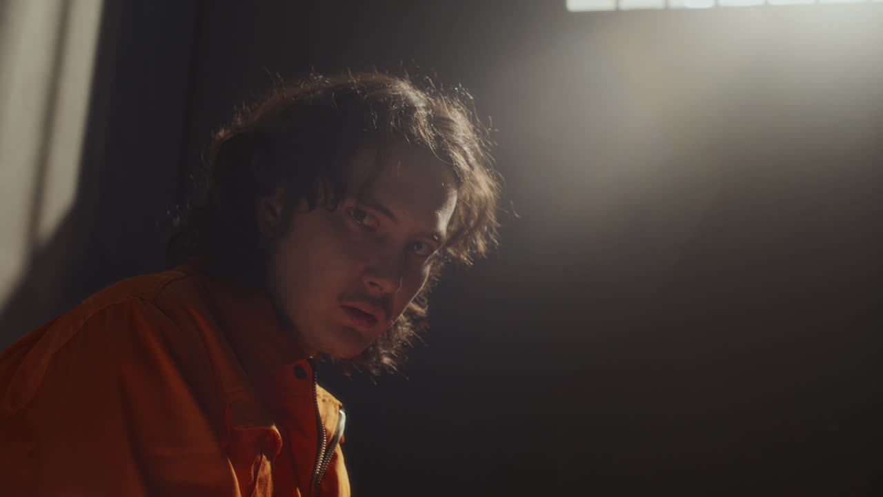 Portrait of Desperate Male Prisoner Sitting in Jail Cell
