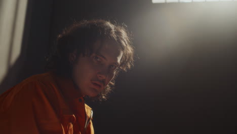 portrait of desperate male prisoner sitting in jail cell