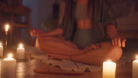 woman meditating in a calm evening atmosphere with candles and incense