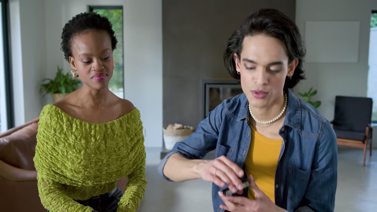 Diverse friends clapping, talking and demonstrating makeup with blush compact and palette at home