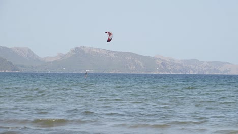 One-Person-is-kiteboarding-in-cear-blue-water-at-Mallorca-Balearic-Islands-surrounded-by-mountain