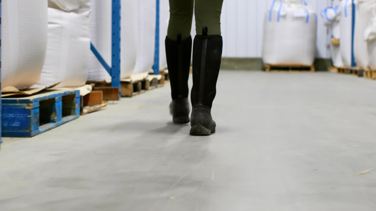 Gambe di un'operaia che cammina in magazzino 4K.