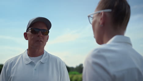 Two-golf-players-talking-at-country-club.-Couple-golfers-discuss-game-on-fairway