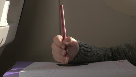 in plane sits a little boy and draws with a pencil on paper