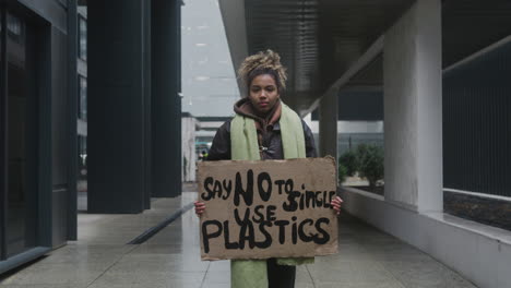 joven activista climático estadounidense sosteniendo un cartel y protestando contra los plásticos de un solo uso mientras mira la cámara 2