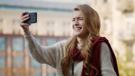 Funny-girl-posing-phone-camera.-Grimacing-woman-taking-selfies-by-phone-outdoors