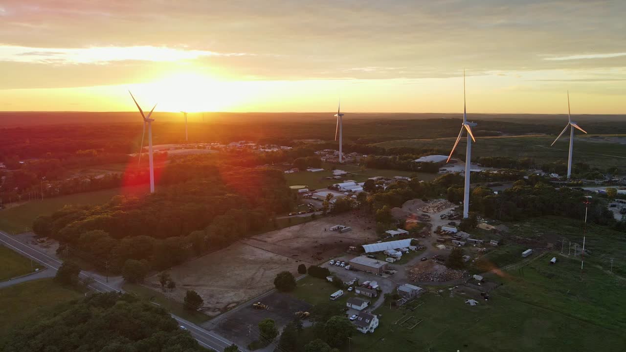 toma aérea de molinos de viento que generan electricidad en rhode island trabajando en la puesta de sol