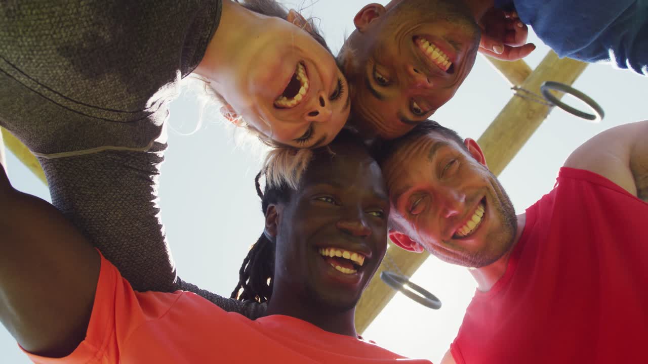 Happy, fit diverse group making a huddle, smiling and touching heads, seen from below