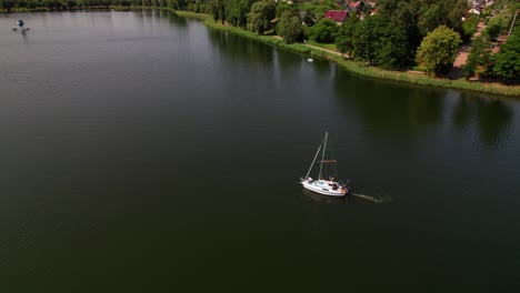 Sailboats-sail-on-a-lake,-distant-drone-parallax-shot