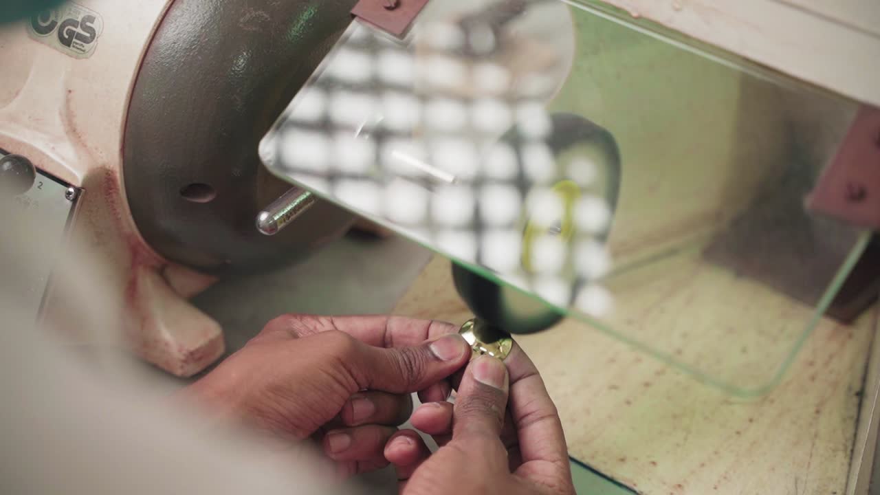 Close up of professional craftsman polishing gold jewellery on workbench, slow motion