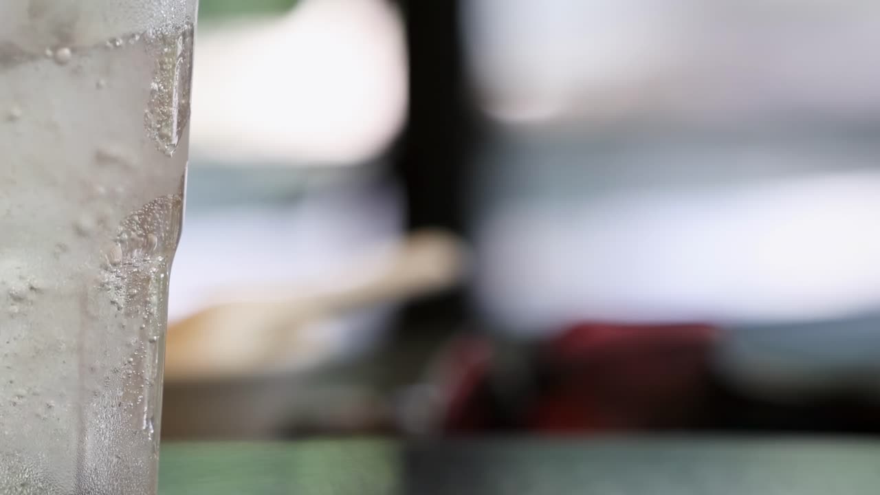 Detailed view of bubbles rising in a transparent glass against a blurred background.