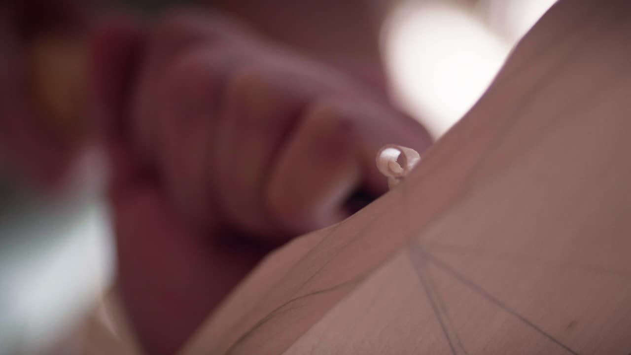 Filo metálico afilado de un cincel tallando madera, creando una fina viruta en espiral en un taller de carpintería. Primer plano a cámara lenta.