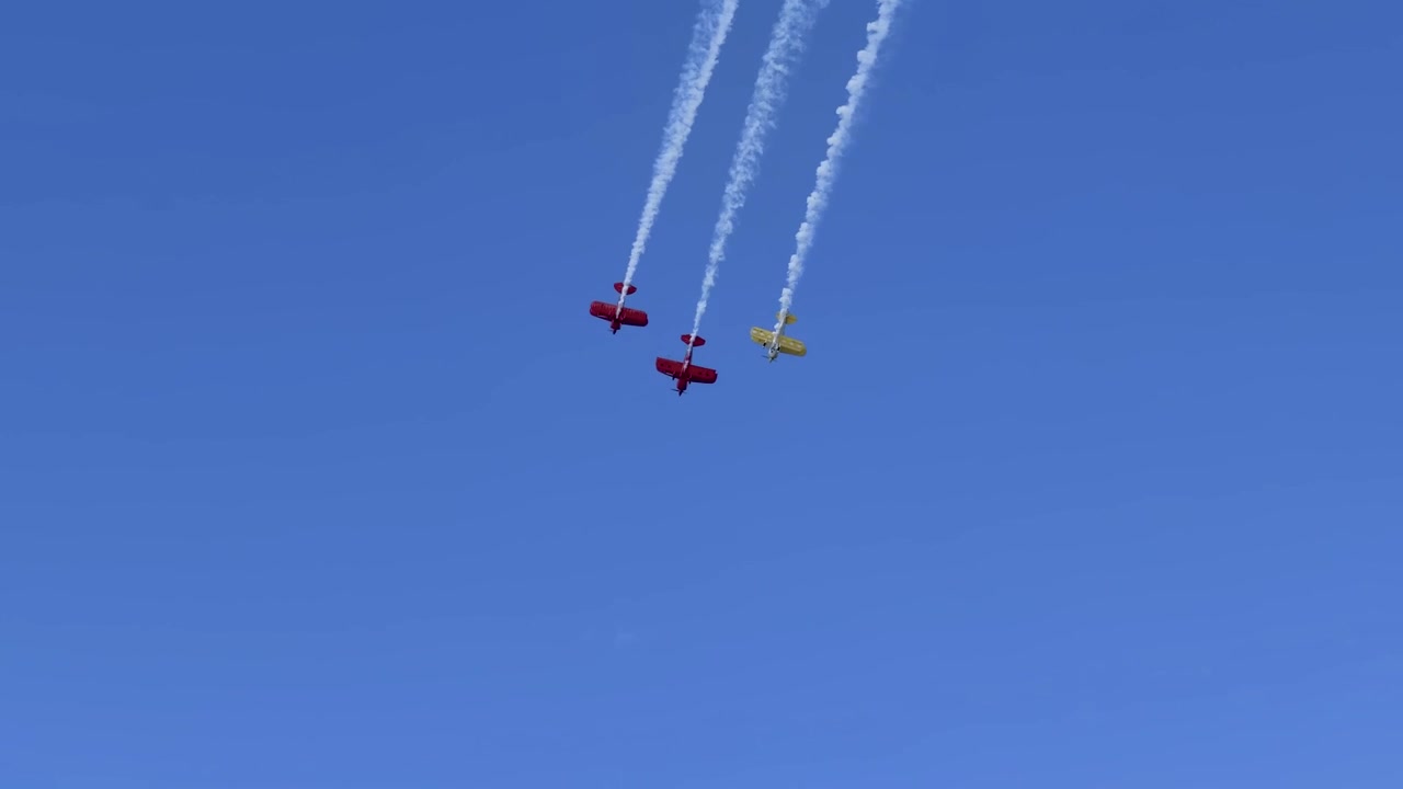 Three stunt planes perform synchronized maneuvers with smoke trails over Gold Coast, Australia.