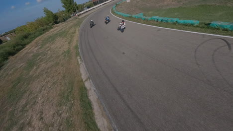 Drone-Fpv-Extremo-Persiguiendo-Motocicletas-En-Las-Esquinas-De-La-Pista-De-Carreras,-Vista-Aérea