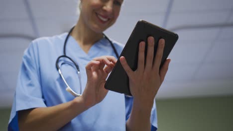 Midsection-of-portrait-of-caucasian-female-doctor-using-digital-tablet-in-hospital-room