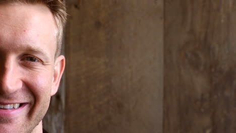 Portrait-of-a-happy-man-smiling-against-a-wooden