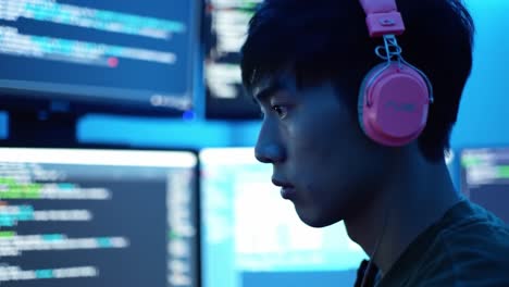 A Focused Individual Analyzing Code on Multiple Monitors in a Dimly Lit Room, Showcasing the Intensity of Modern Technology and Cybersecurity Efforts