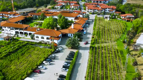 Aerial-view-rising-above-luxury-Starosel-Wine-and-spa-complex-terracotta-tiled-rooftops-and-vineyard,-Bulgaria