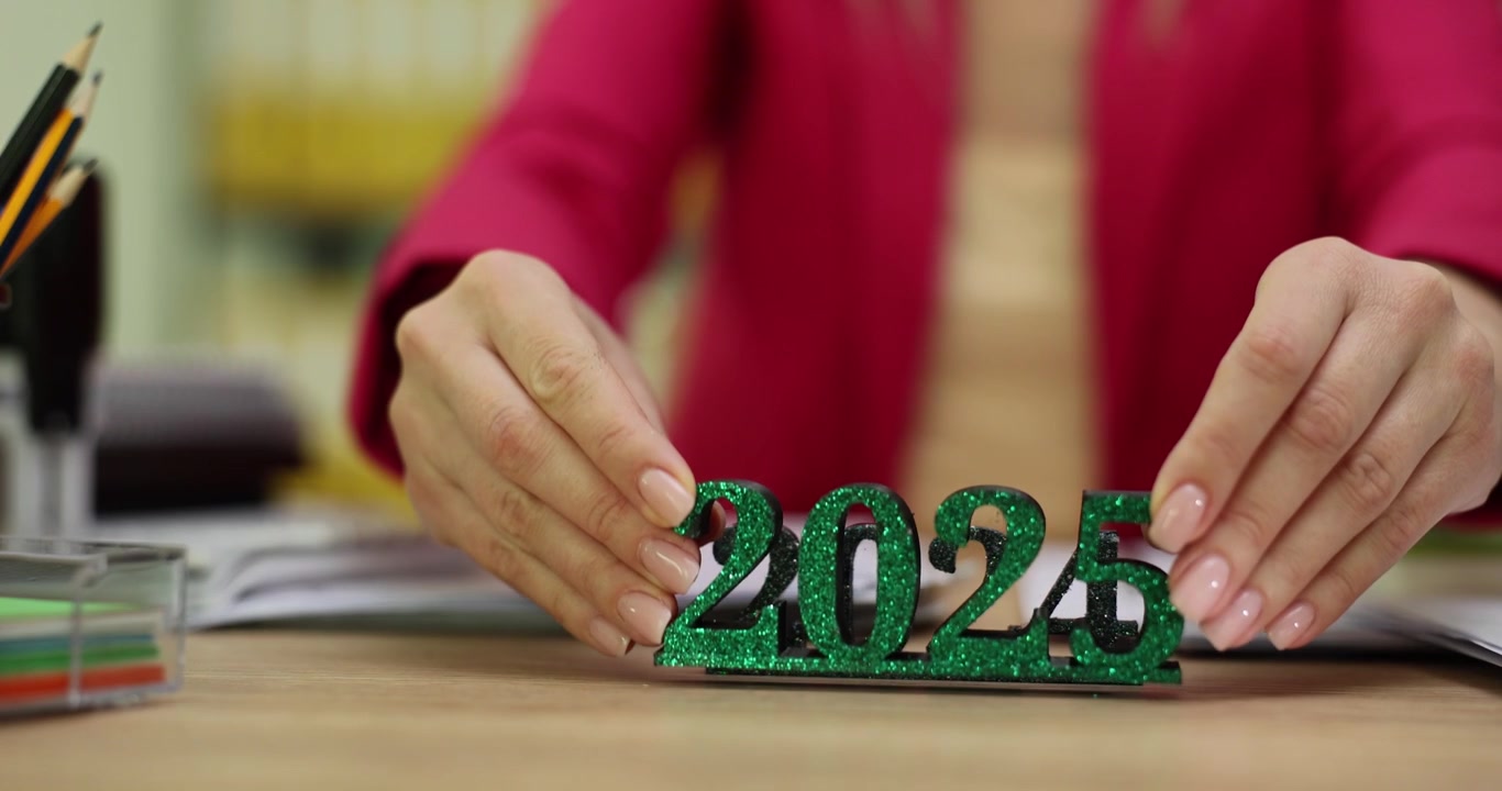 Donna d'affari posiziona una statuetta brillante del 2025 davanti al 2024