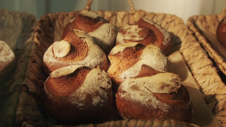 Fresh artesian bread on bakery shop close-up. Bread with black poppy garnish on top and white flour on top. Artisan bread is making by skill bakers using natural and high-quality ingredients. Food with health and flavour benefits.