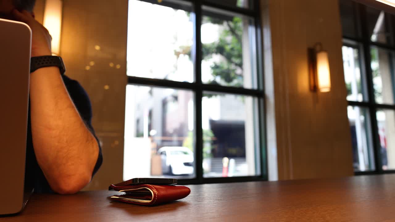 Il braccio di una persona e un portatile su un tavolino di un bar