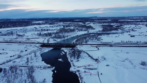 aerial footage of a snowy river and park in the city limits