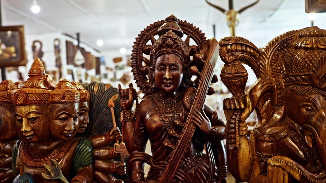Estátuas de madeira detalhadas de divindades hindus, incluindo Saraswati e Ganesh, estão em exibição em uma loja de artesanato no Sri Lanka. Cada figura é esculpida em um único bloco de madeira.