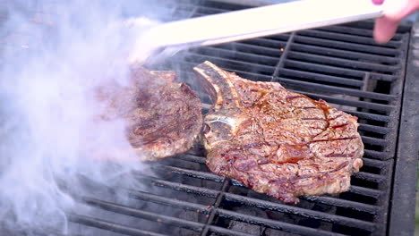 turning steaks on a hot charcoal barbecue with some open flames in a slow zoom in motion