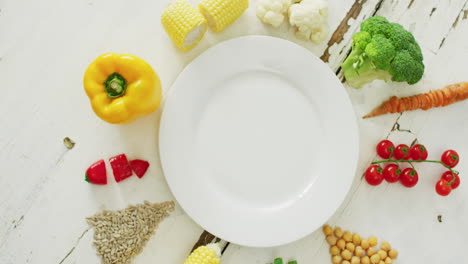 Vídeo-De-Verduras-Frescas-Dispuestas-Alrededor-De-Un-Plato-Blanco-Con-Espacio-Para-Copiar-Sobre-Fondo-Rústico-Blanco