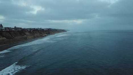 Blick-Von-Einer-über-Das-Meer-Fliegenden-Drohne,-Die-Den-Strand-Auf-Der-Linken-Seite-Zeigt