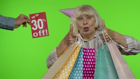 inscription up to 30 percent off appears next to grandmother. woman celebrating with shopping bags