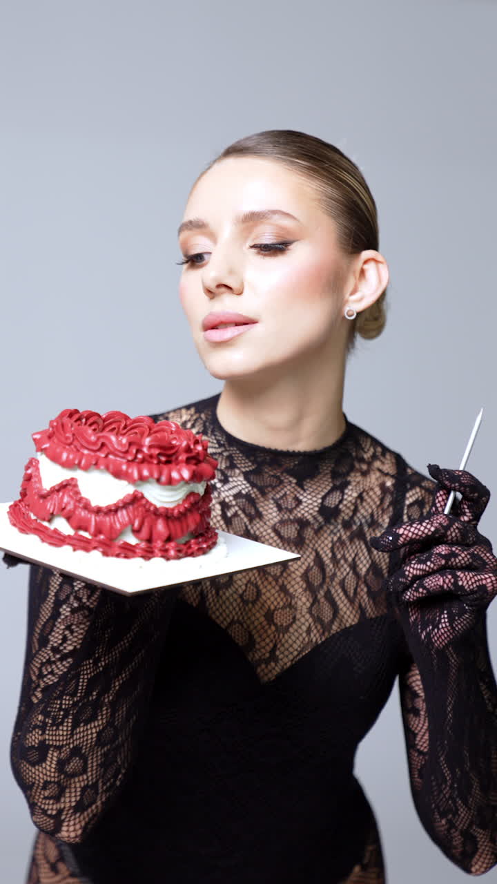 Attractive Caucasian model in stocking lace outfit holding a cake. Lady poses for a photo in studio. Vertical video.