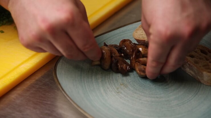 Chef Arranging Cooked Mushrooms and Bread on a Plate