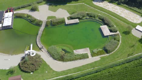 pareja de hombres y mujeres montando en bicicleta alrededor de un lago con un puente, tiro de seguimiento de vista de pájaro de drones aéreos, parque de vodni de eslovenia