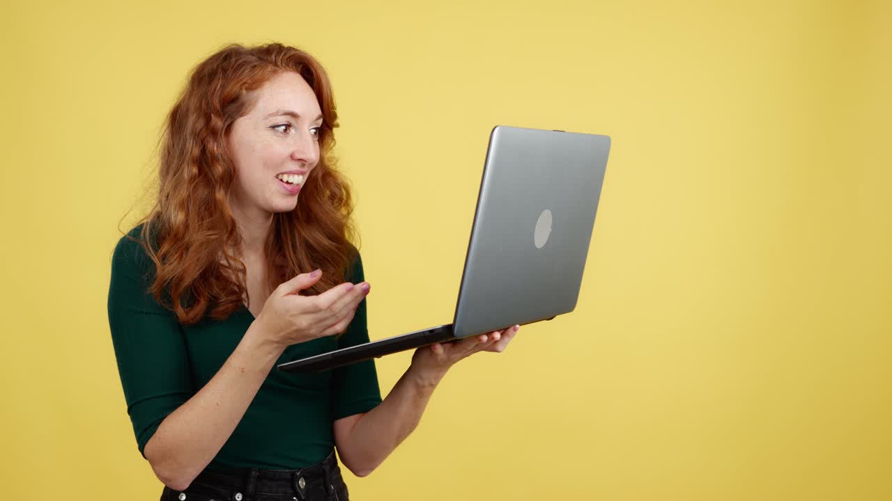 Red-haired woman reacting with surprise and amusement while holding a laptop