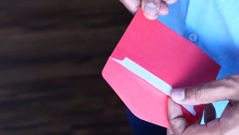 persona abriendo un sobre rojo con una nota de agradecimiento