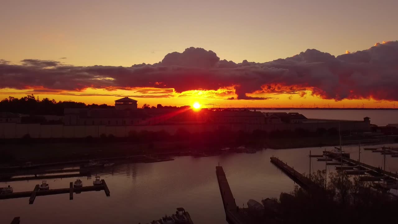 Fiery red, yellow and orange sunburst sunrise seen from a marina
