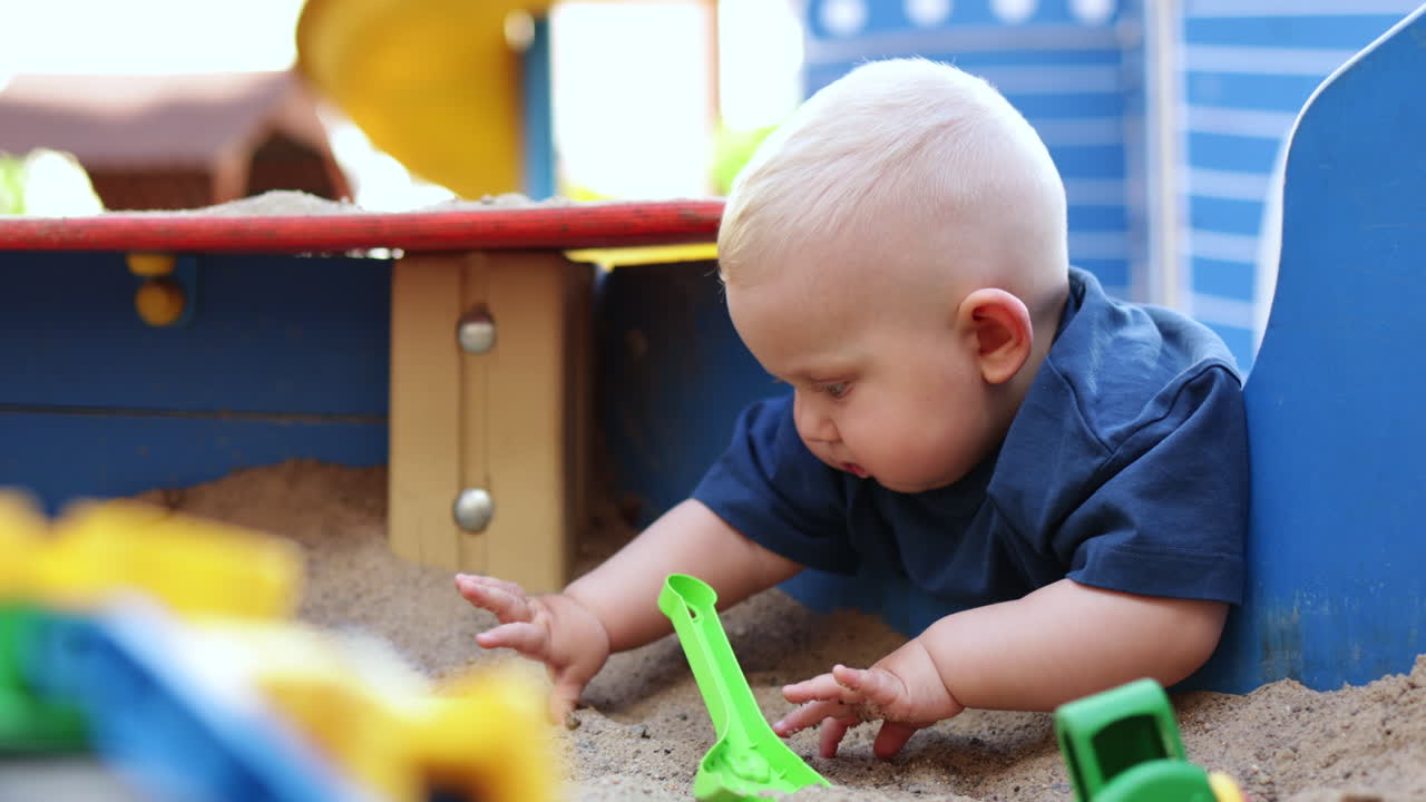 Baby boy playing with sand outdoors. Child development. Children's games on the playground